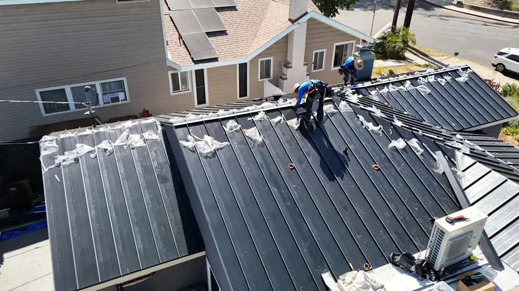 Crew member installing black standing seam panels on a Los Angeles home