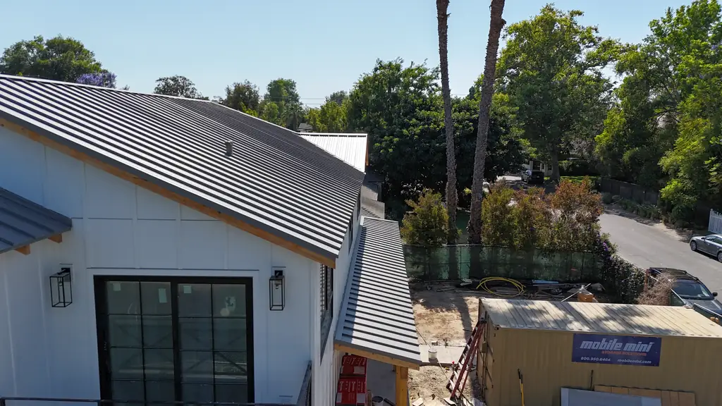 Finished gray standing seam roof over a white board-and-batten house