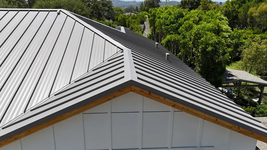 Finished gray standing seam roof over a white gable with straight, evenly spaced seams