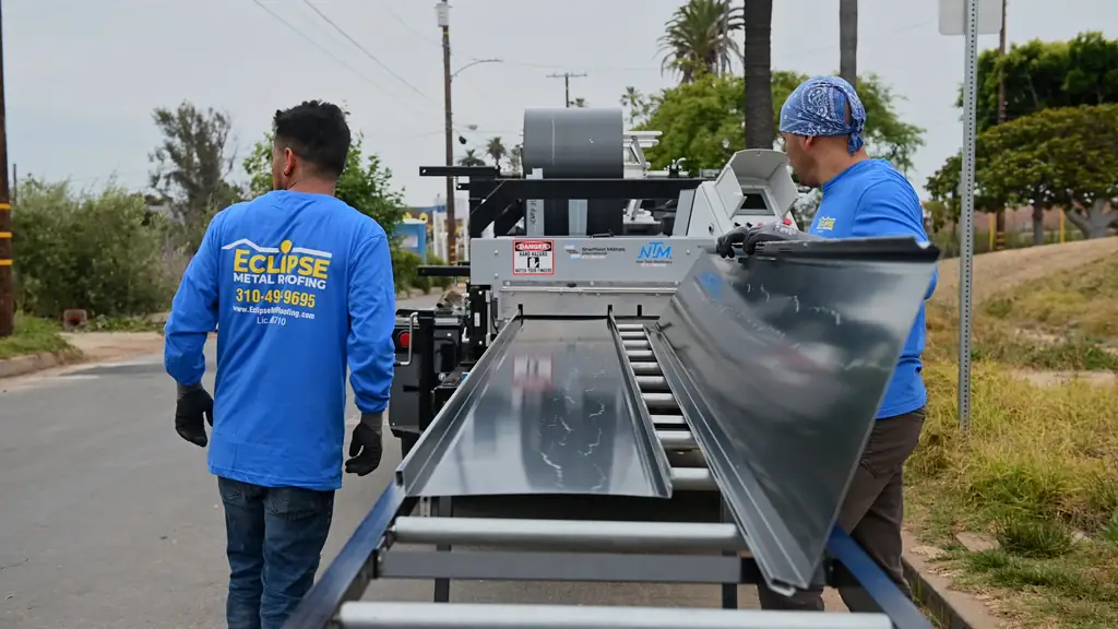 Eclipse Metal Roofing crew lifting a long standing seam panel from the roll former run-out table