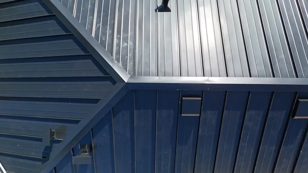 Close view of black standing seam panels meeting at a hip, with straight raised seams